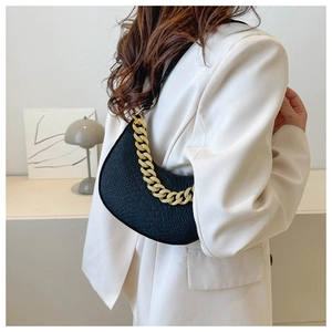 Detail of black lizard-embossed hobo bag with thick gold chain on cream suit jacket