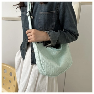 Detail of mint green pleated cloud bag featuring wavy texture and adjustable fabric strap