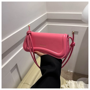 Detail einer pinken Halbmond-Tasche mit goldenem Logo und geknotetem Schulterriemen