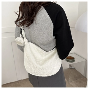 Detail of white quilted crescent bag with a round coin purse in a modern minimalist setting