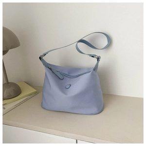 Hellblaue Nylon-Einkaufstasche mit Reißverschluss und Dekoschnalle auf minimalistischem Tisch