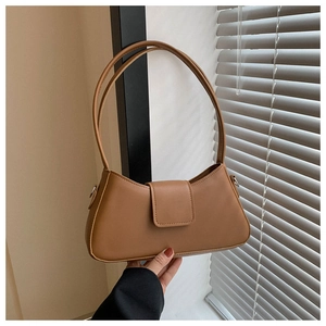 Close-up of caramel faux leather shoulder bag featuring silver metal rings and flap