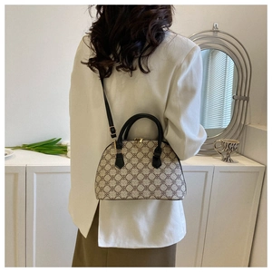 Detailed view of beige monogram shell bag with black leather straps on a model