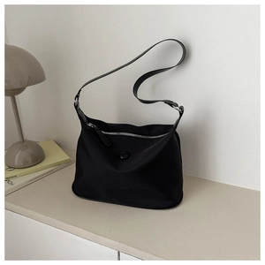 Detail der minimalistischen schwarzen Nylontasche mit Silber-Reißverschluss und Dekoknopf