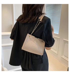 Model wearing a beige quilted felt crossbody bag with a stylish gold chain strap