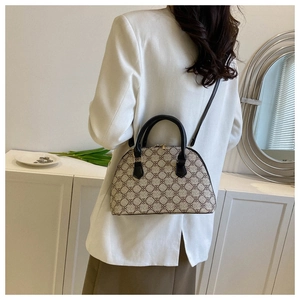 Minimalist beige shell handbag with geometric pattern shown on model in a white suit
