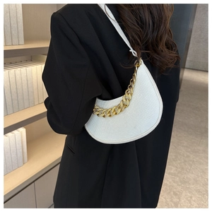 White crescent underarm bag featuring a chunky gold chain strap worn by a model