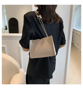 Detail of beige quilted chain shoulder bag worn by model in a minimalist modern interior