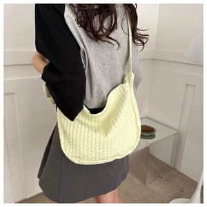 Model wearing a yellow crescent shoulder bag with bubble pleat texture and wide strap