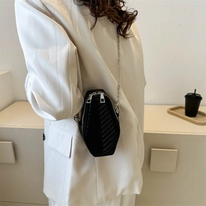 Fashionable black coffin-shaped quilted crossbody bag with silver chains worn by model