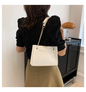 Chic white quilted felt crossbody bag with golden chain strap shown on a model