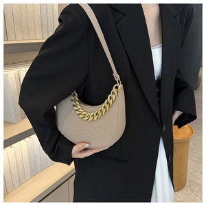 Detail of hobo bag in beige with gold chain strap and textured fabric material