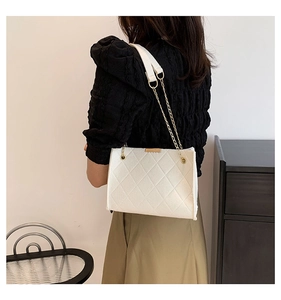 White quilted tote bag with golden chain strap shown in a modern lifestyle setting