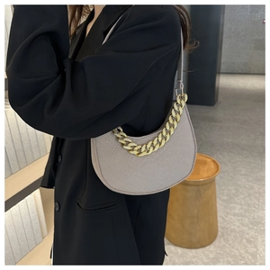 Detail of grey felt crescent shoulder bag with chunky gold chain strap on model