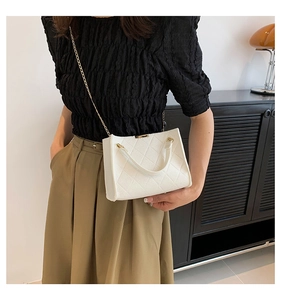 Close-up of white quilted crossbody bag with gold chain strap on a model