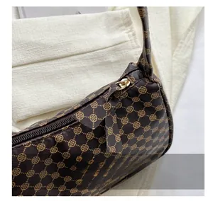 Close-up of smooth gold metal zipper and vintage clover pattern on brown leather bag