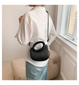 Détail d'un sac demi-lune plissé noir avec des finitions en métal doré sur un modèle