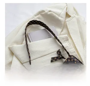 Detail view of brown vintage monogram handbag with bow accent on a cream blazer