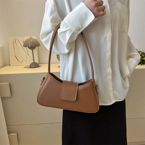 Chic caramel brown baguette shoulder bag in matte leather shown on a model in a minimalist setting