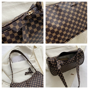 Detail view of brown vintage print handbag with metal zipper and leather texture