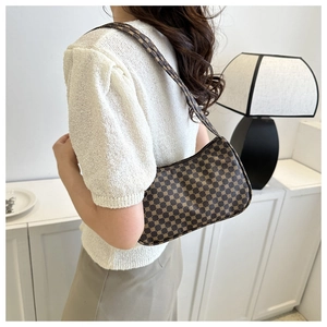 Detailed view of a brown vintage shoulder bag with geometric patterns worn by a model