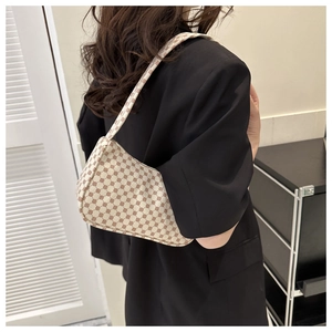 Minimalist beige moon bag with brown geometric pattern worn by model in black blazer
