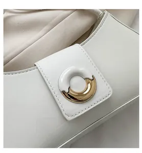 Detailed close-up of premium cream leather texture and golden round metal buckle on handbag