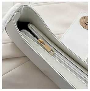 Close-up of smooth gold zipper and magnetic closure on the white PU leather handbag
