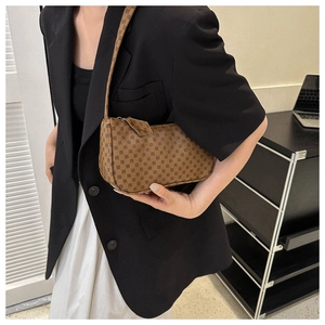 Close-up of retro brown hobo bag with geometric monogram pattern on a fashion model