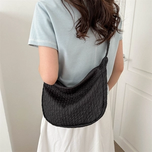 Chic black quilted crescent crossbody bag shown on model in a minimalist urban setting