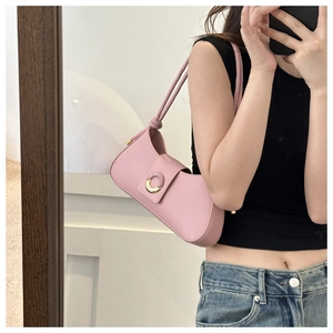 Detailed shot of a pink leather underarm bag with a golden circular decorative buckle