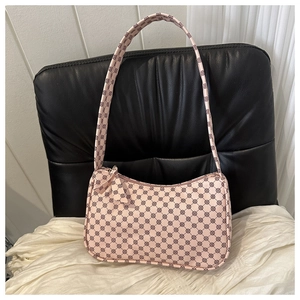 Detailed close-up of pink crescent underarm bag with circular logo print and bow zipper