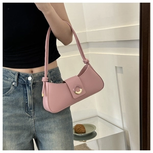 Detail of pink baguette bag featuring a gold crescent buckle and knotted shoulder strap
