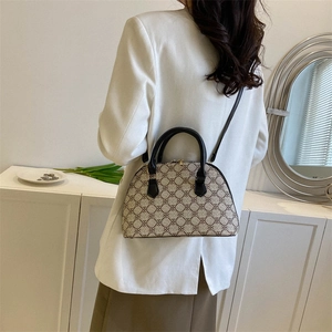 Classic shell-shaped handbag in brown monogram pattern with black handles and shoulder strap