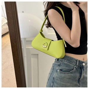 Close-up of bright green shoulder bag with knotted strap and round metal buckle detail