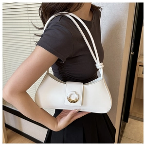 Detail of pearl white underarm bag with gold ring buckle and knot strap on model