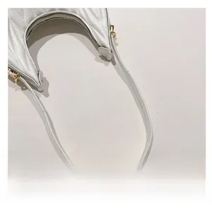 Close-up of quilted leather crescent bag handle with gold hardware and stitching detail