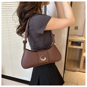 Close-up of a dark brown shoulder bag with a unique knot strap and round resin buckle