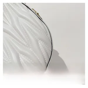 Detail of white quilted leather texture and premium gold zipper on a crescent bag