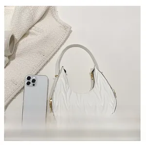 Size comparison of a white matelassé hobo bag next to a smartphone showing scale