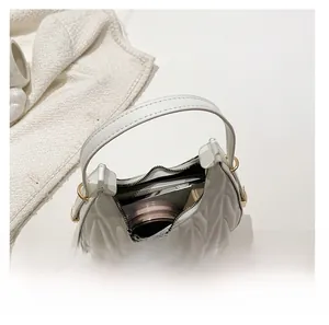 Detail view of the spacious interior of a white quilted crescent bag with daily essentials