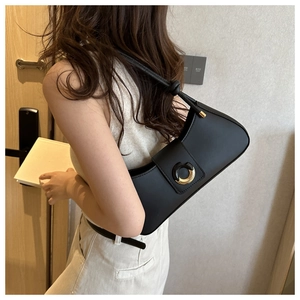 Detail of minimalist black hobo bag with a distinctive gold and black circular buckle