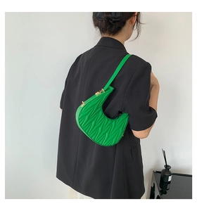 Detail of bright green crescent bag featuring V-shaped quilted pleats and gold hardware