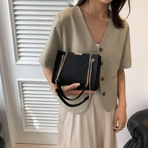 Elegant black quilted felt chain bag with gold hardware for women, shown by model