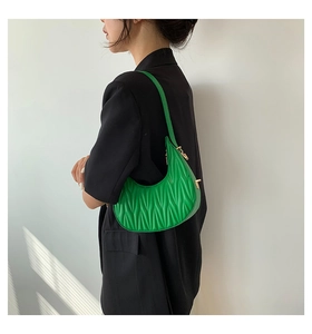 Detail of bright green matelasse crescent bag with golden zipper on model shoulder