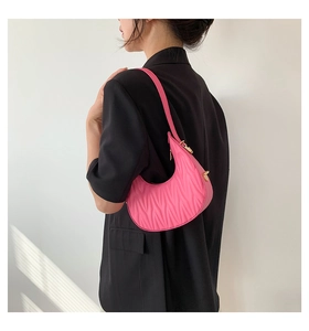Detailed shoulder view of a pink crescent bag with vertical quilted texture and gold zipper