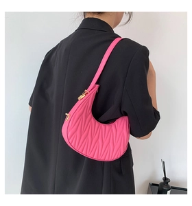 Detail of fuchsia pleated crescent shoulder bag with golden hardware on black blazer