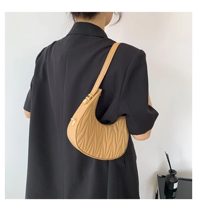 Fashionable camel crescent underarm bag with unique wave quilted texture on a black blazer