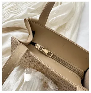 Detail view of smooth golden zipper and lining on hand-woven straw tote bag for women