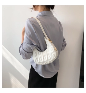 Detail of white crescent bag with V-shaped quilted stitching on a female model